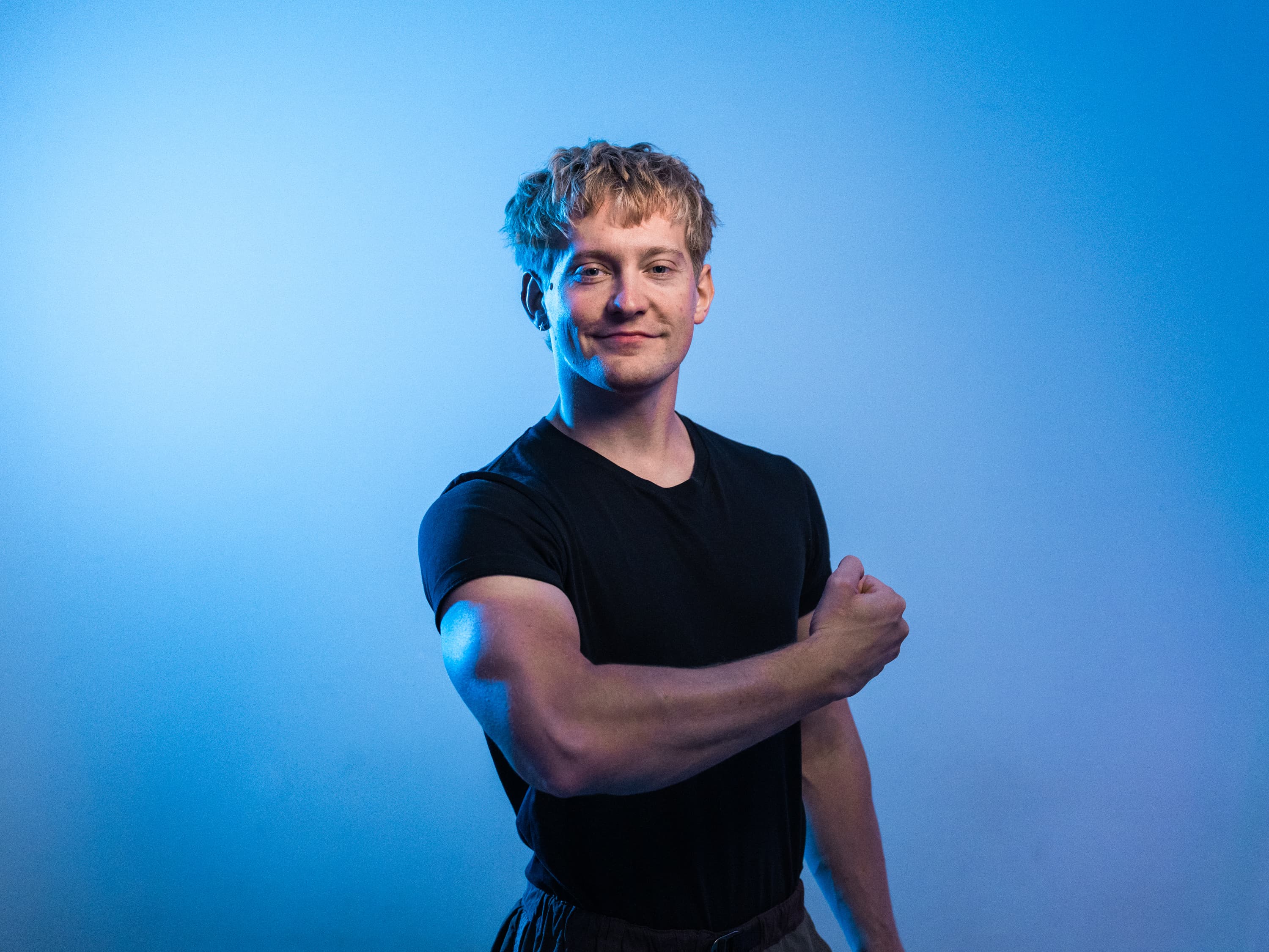Stefan, your coach, in a black T-shirt against a blue studio background